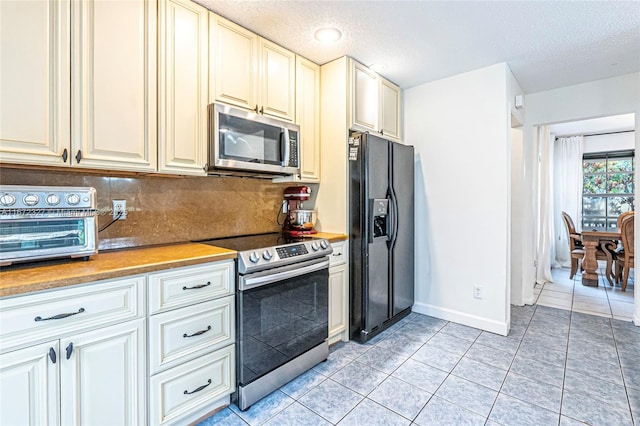 2913 Myrtle Oak Cir, Davie, FL 33328 - kitchen with appliances with stainless steel finishes, backsplash, light tile patterned flooring, cream cabinets, and a textured ceiling