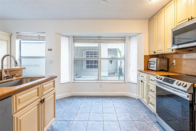 kitchen with appliances with stainless steel finishes, tasteful backsplash, a healthy amount of sunlight, and sink