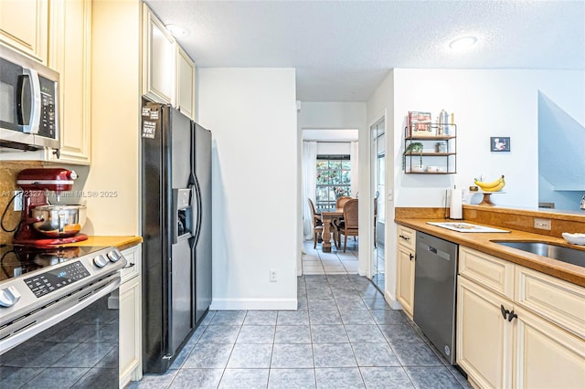 2913 Myrtle Oak Cir, Davie, FL 33328 - kitchen featuring appliances with stainless steel finishes, cream cabinets, a textured ceiling, light tile patterned floors, and wood counters
