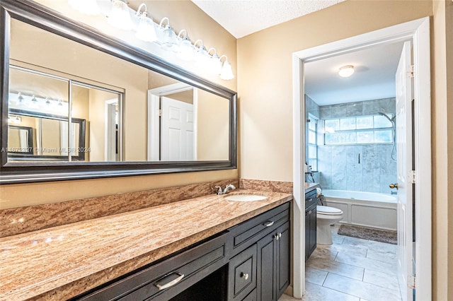 full bathroom with tile patterned floors, a textured ceiling, vanity, toilet, and tiled shower / bath