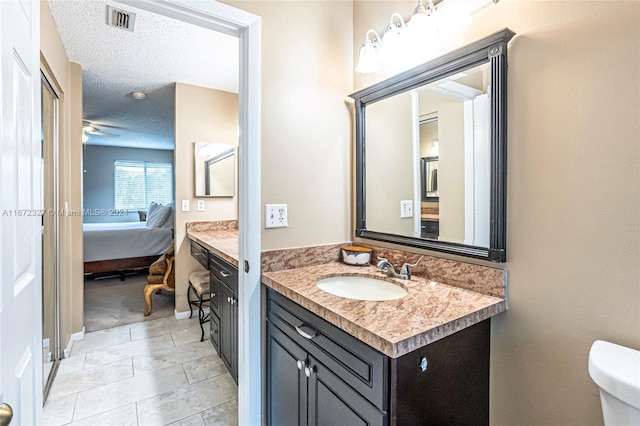 bathroom featuring tile patterned flooring, vanity, a textured ceiling, and toilet