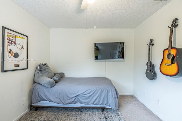 carpeted bedroom featuring ceiling fan and a textured ceiling