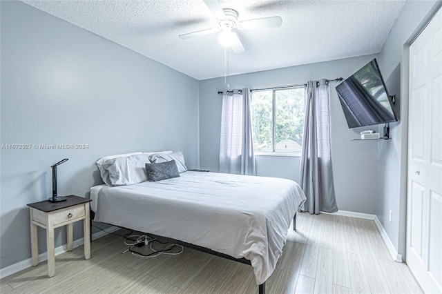 bedroom with a textured ceiling, a closet, light hardwood / wood-style flooring, and ceiling fan