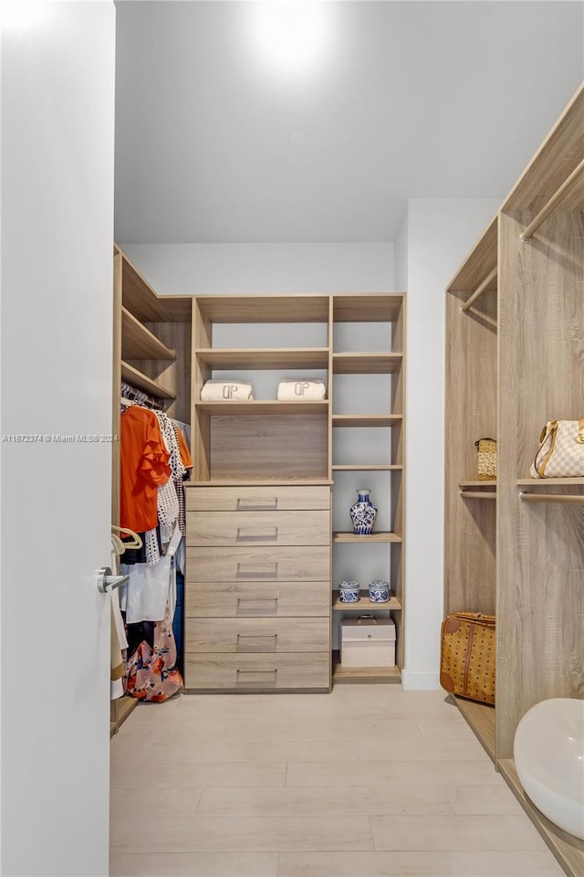 walk in closet with light hardwood / wood-style flooring