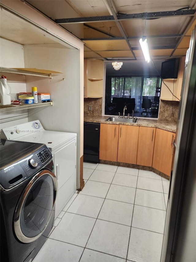 washroom with washing machine and clothes dryer, an inviting chandelier, light tile patterned floors, and sink