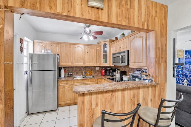 kitchen with backsplash, kitchen peninsula, a breakfast bar area, stainless steel appliances, and sink