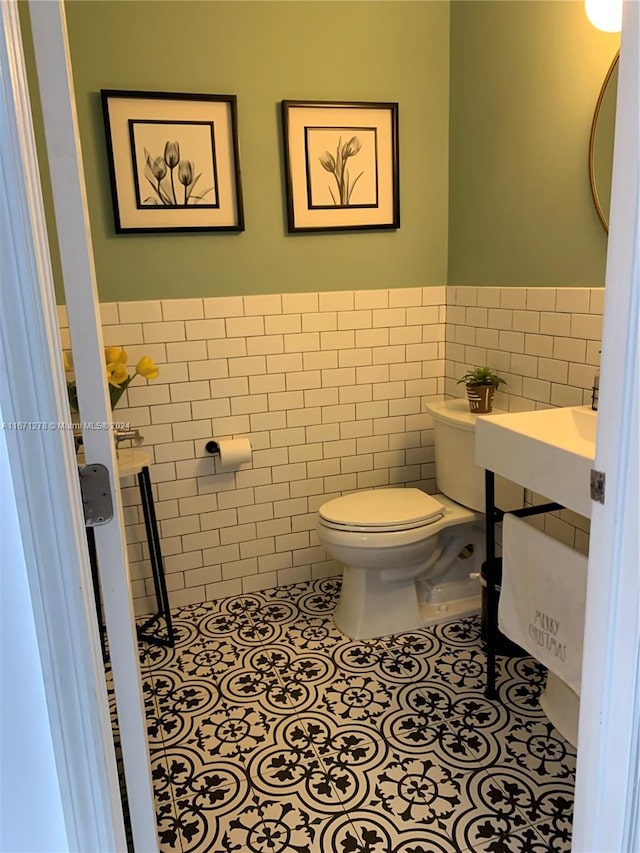 bathroom featuring toilet, tile walls, and tile patterned flooring