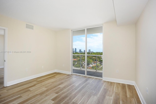 empty room featuring light wood-type flooring, a healthy amount of sunlight, and a wall of windows