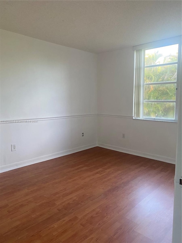 spare room featuring a textured ceiling and dark wood-type flooring