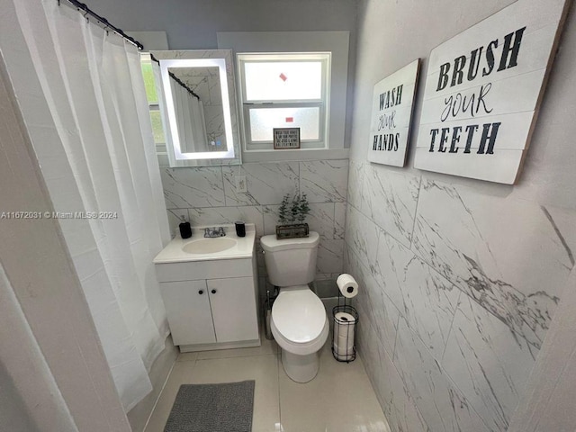 bathroom with vanity, tile patterned floors, walk in shower, tile walls, and toilet