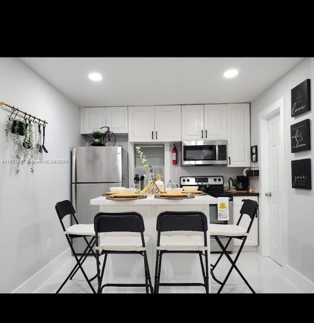 kitchen featuring stainless steel appliances, white cabinetry, and a kitchen bar