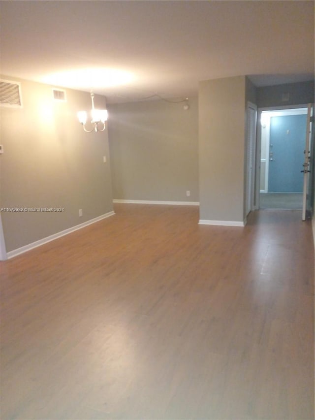 unfurnished room with an inviting chandelier and hardwood / wood-style floors