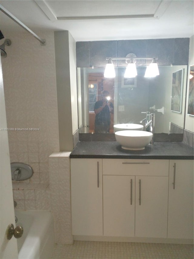 bathroom with tiled shower / bath, vanity, tile walls, and tile patterned floors