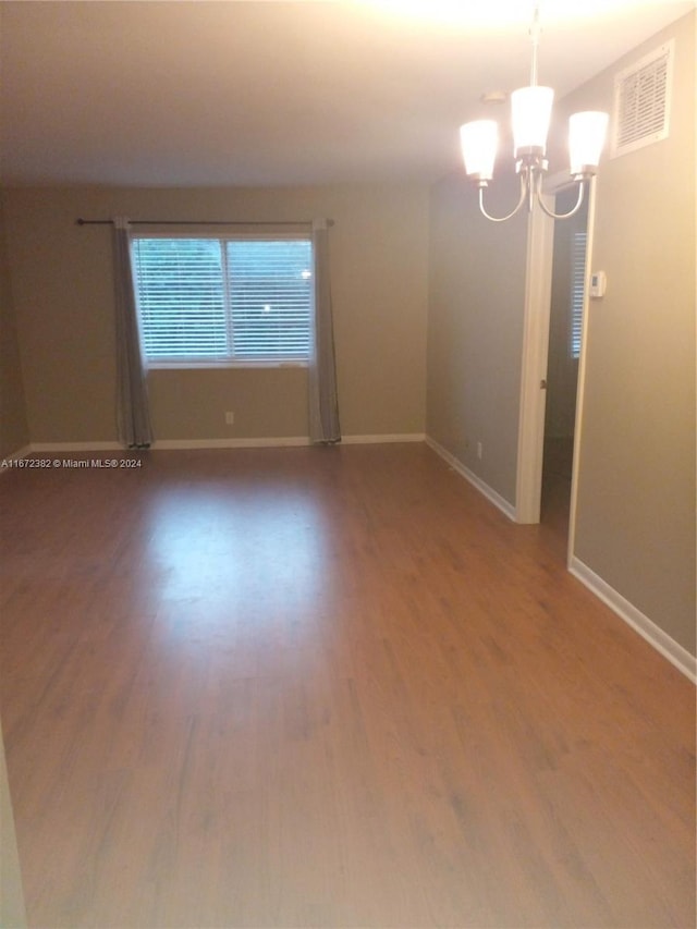 empty room featuring an inviting chandelier and hardwood / wood-style floors