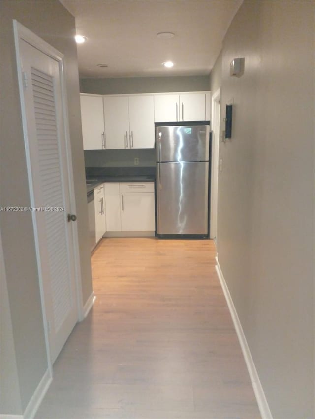 kitchen featuring stainless steel refrigerator, light hardwood / wood-style floors, and white cabinetry