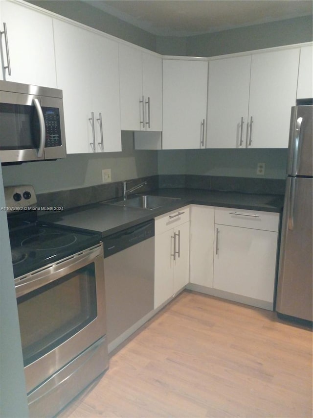 kitchen featuring stainless steel appliances, white cabinets, light wood-type flooring, and sink