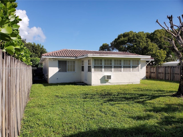 rear view of property featuring a lawn and a wall unit AC