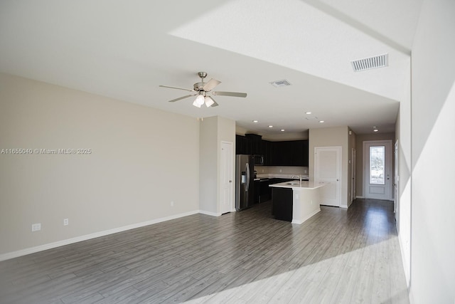 kitchen featuring stainless steel refrigerator with ice dispenser, sink, dark hardwood / wood-style flooring, an island with sink, and ceiling fan