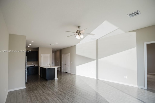 unfurnished living room featuring ceiling fan, dark hardwood / wood-style flooring, and sink