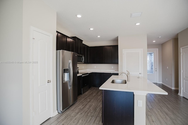 kitchen with stainless steel appliances, sink, an island with sink, and light hardwood / wood-style flooring