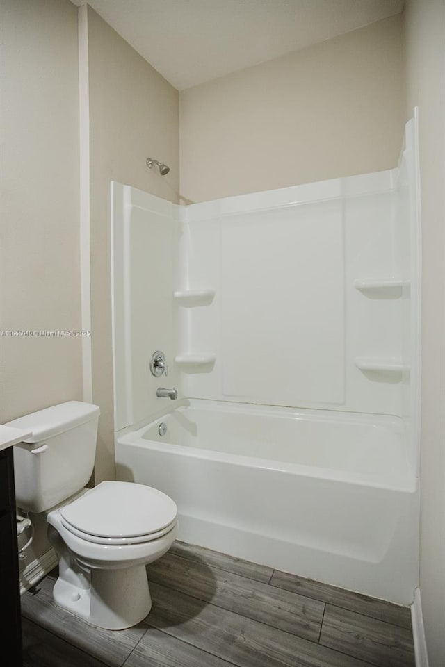 bathroom with shower / washtub combination, hardwood / wood-style floors, and toilet