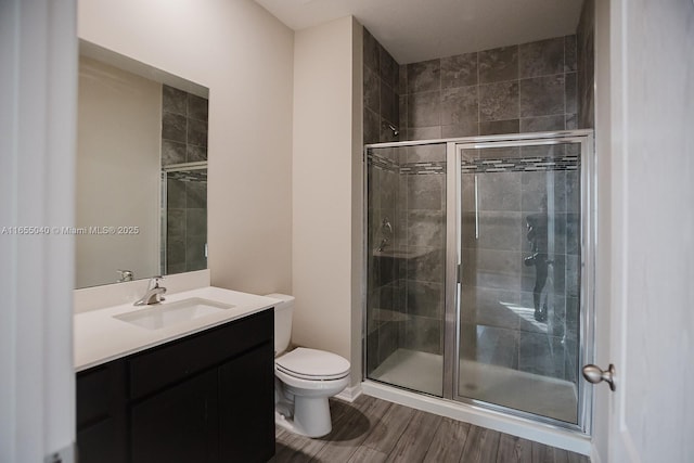 bathroom with an enclosed shower, vanity, hardwood / wood-style flooring, and toilet