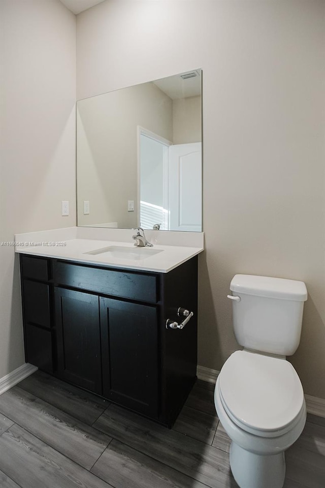 bathroom featuring vanity, wood-type flooring, and toilet