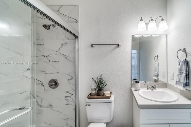 bathroom featuring toilet, a textured wall, a marble finish shower, and vanity