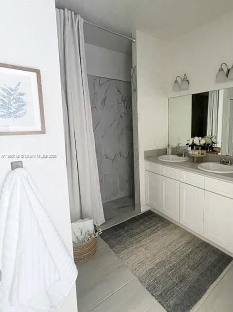 full bathroom featuring double vanity, a sink, and a marble finish shower