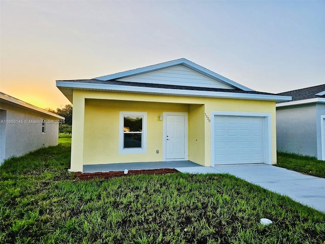 view of front of house with a yard, concrete driveway, an attached garage, and stucco siding