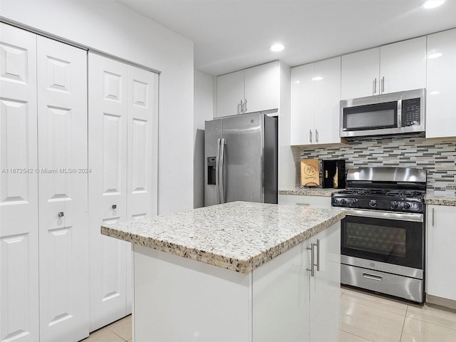 kitchen featuring a center island, decorative backsplash, light tile patterned floors, white cabinetry, and stainless steel appliances