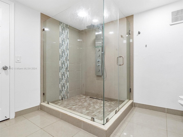 bathroom with tile patterned flooring, toilet, and a shower with door