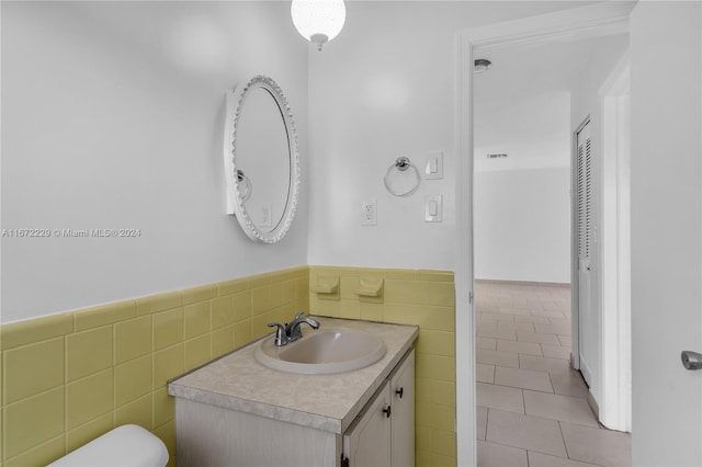 bathroom featuring tile patterned flooring, vanity, toilet, and tile walls