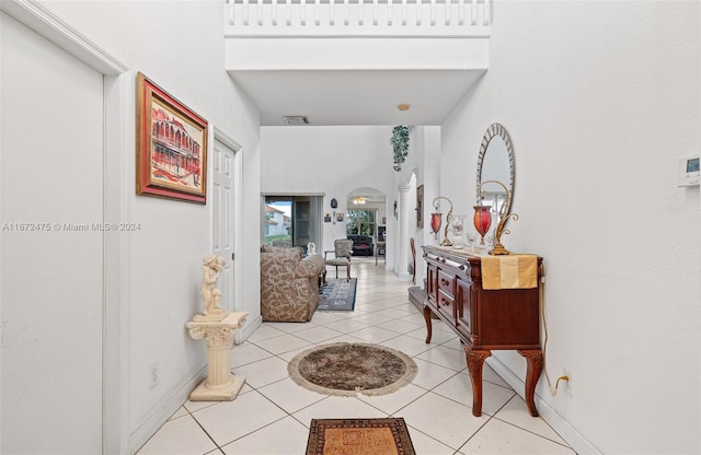 hall featuring a towering ceiling and light tile patterned floors