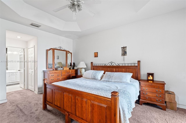 carpeted bedroom featuring connected bathroom, ceiling fan, and a raised ceiling