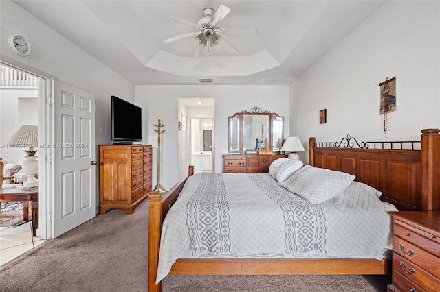 carpeted bedroom featuring connected bathroom, ceiling fan, and a raised ceiling