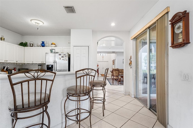 kitchen with light tile patterned floors, stainless steel fridge with ice dispenser, and white cabinets