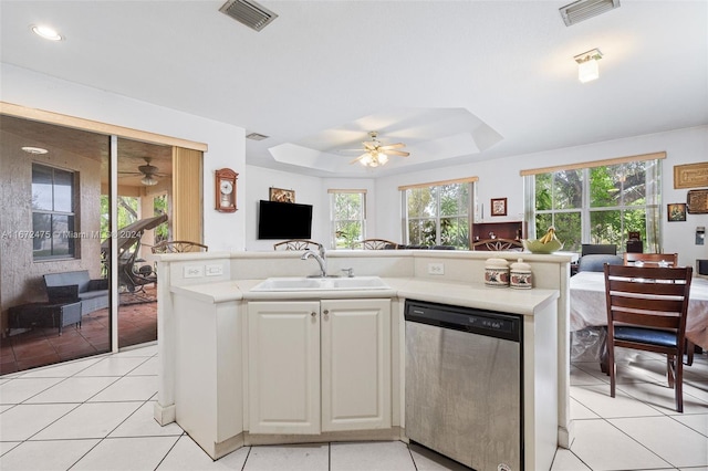 kitchen with light tile patterned floors, dishwasher, a tray ceiling, and sink