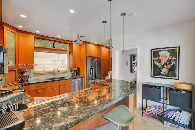 kitchen featuring pendant lighting, sink, a breakfast bar, stainless steel appliances, and dark stone counters