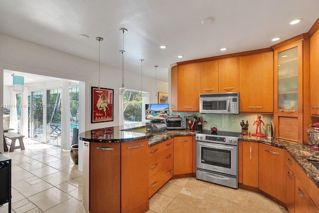 kitchen featuring pendant lighting, appliances with stainless steel finishes, kitchen peninsula, and dark stone countertops