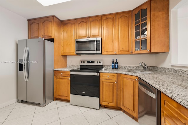 kitchen featuring appliances with stainless steel finishes, light stone countertops, light tile patterned flooring, and sink