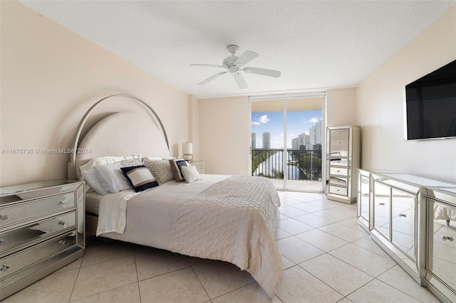 bedroom with a textured ceiling, light tile patterned flooring, access to outside, ceiling fan, and a wall of windows