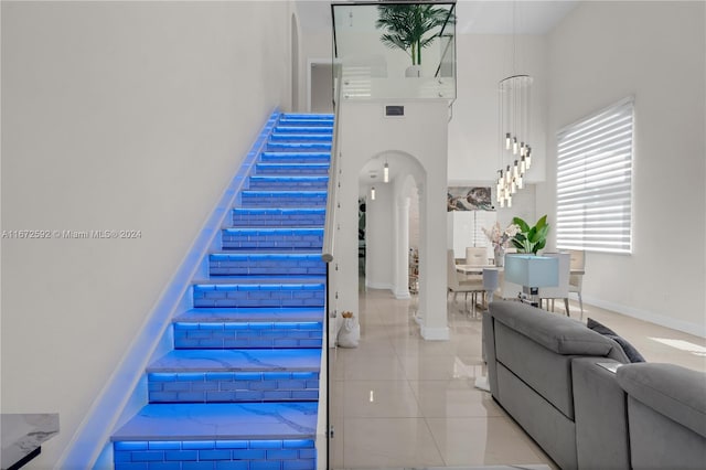 staircase with a towering ceiling and tile patterned floors