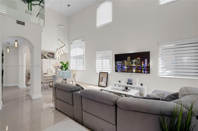 living room featuring a high ceiling, light tile patterned flooring, and ornate columns