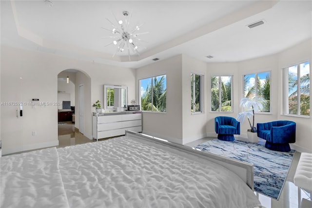 bedroom with an inviting chandelier, a tray ceiling, and multiple windows