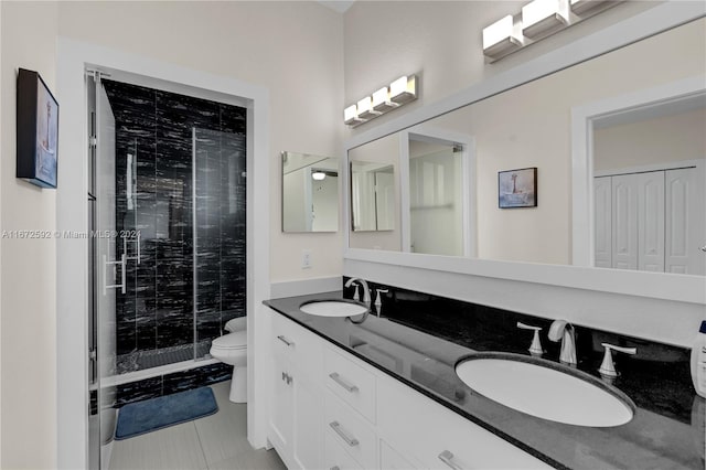 bathroom featuring tile patterned flooring, a shower with door, vanity, and toilet