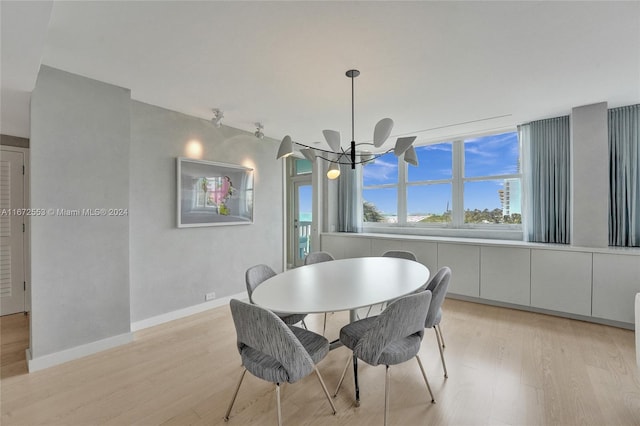 dining area with light wood-type flooring and a chandelier