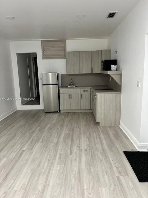 kitchen featuring light brown cabinetry, stainless steel refrigerator, and light wood-type flooring