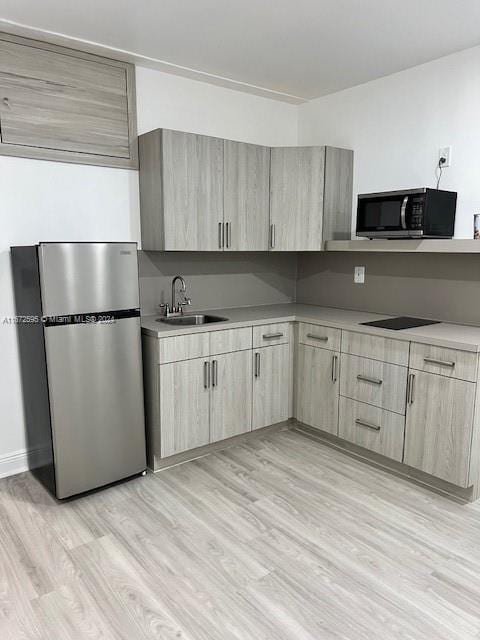 kitchen featuring black appliances, light hardwood / wood-style floors, light brown cabinets, and sink