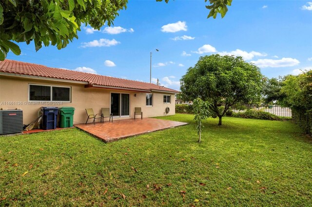 rear view of property featuring a yard, central AC, and a patio area